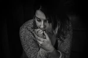 Black and white photo of woman looking anxious biting on her fingernails