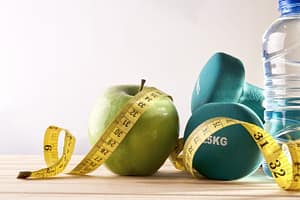 an apple, weights, bottled water and measuring tape