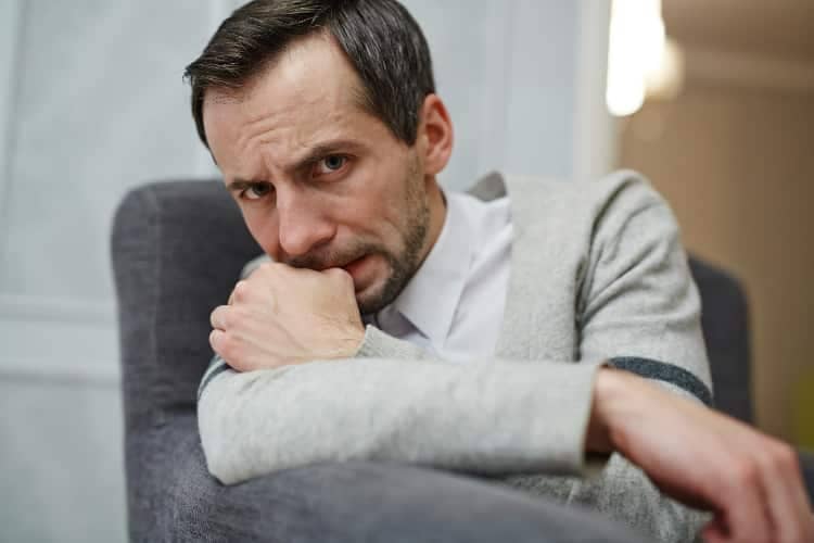 Anxious man biting on finger nail in therapy session