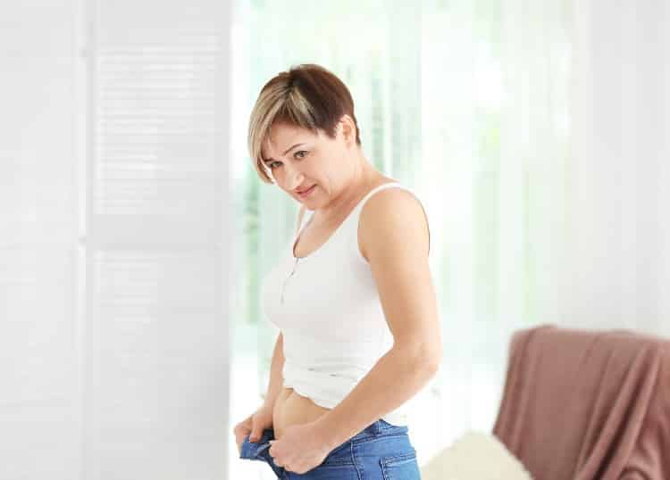 Woman having trouble fitting pants over her belly