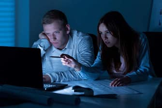 Tired couple working on a computer late into the evening