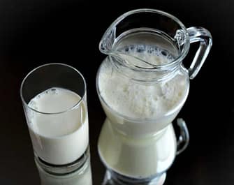 Pitcher and glass of milk resting on a mirror