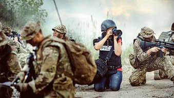 War correspondent taking pictures among soldiers in combat