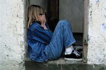 Young girl with hands over her face hiding in a doorway