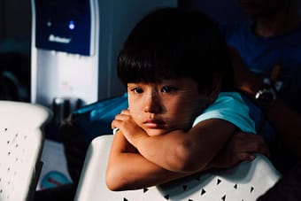 Sad child leaning over the back of the chair