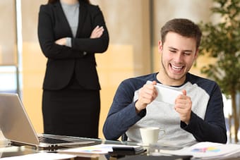 Procrastinating office worker playing on phone in front of boss