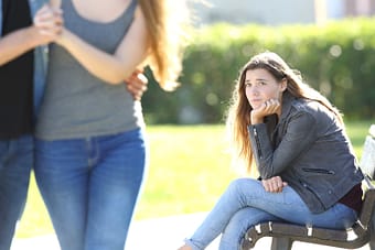 Sad girl looking longingly at couple walking by