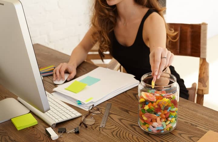 woman at work snacking from candy jar