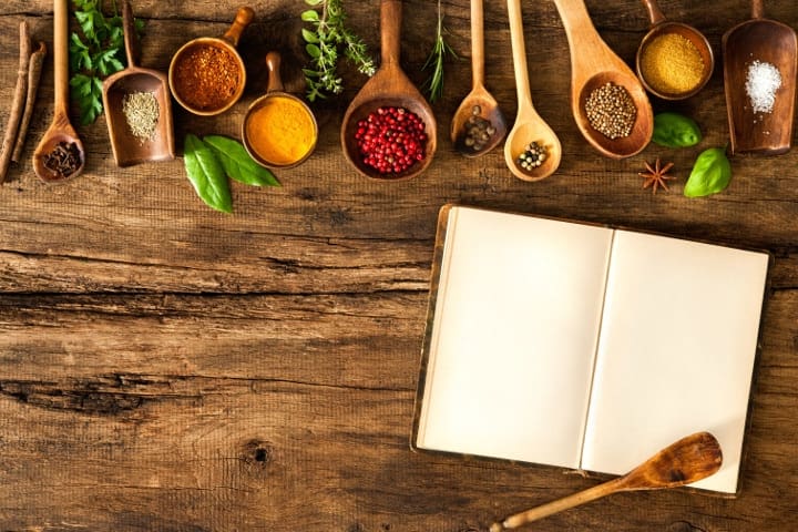 spoons filled with ingredients on table with cookbook