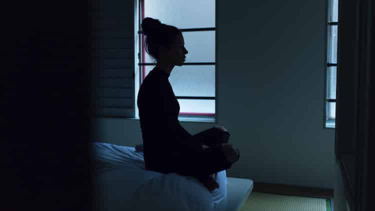 young woman performing sleep meditation in a darkened room