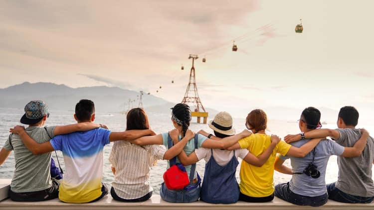 Group of young people having a group hug by the sea shore