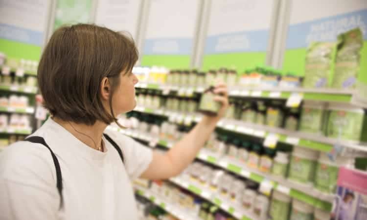 Woman looks at bottle of natural supplement in health food store