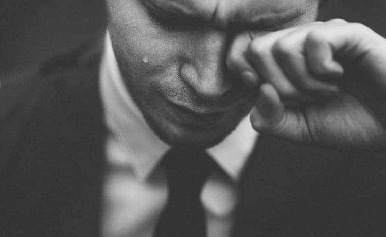 Man in business suit wiping tears from his eyes