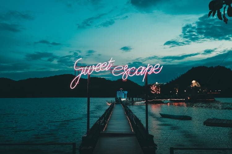 Sweet escape neon sign in front of dock at sunset
