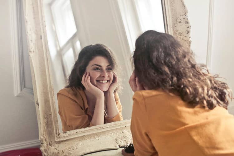 Happy woman looking at her reflection in a mirror