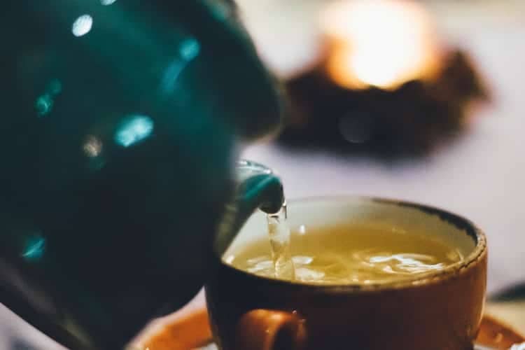 Tea pot pouring tea into a cup