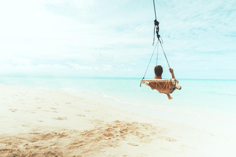 Man relaxing in hanging chair by tropical seashore