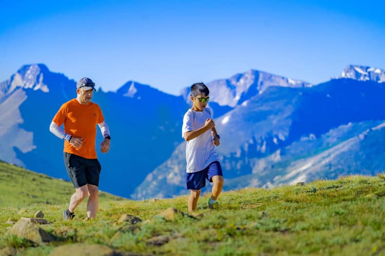 Older man and younger boy running on mountain trail