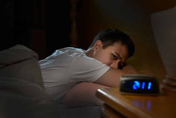 man with insomnia staring at alarm clock in the early morning