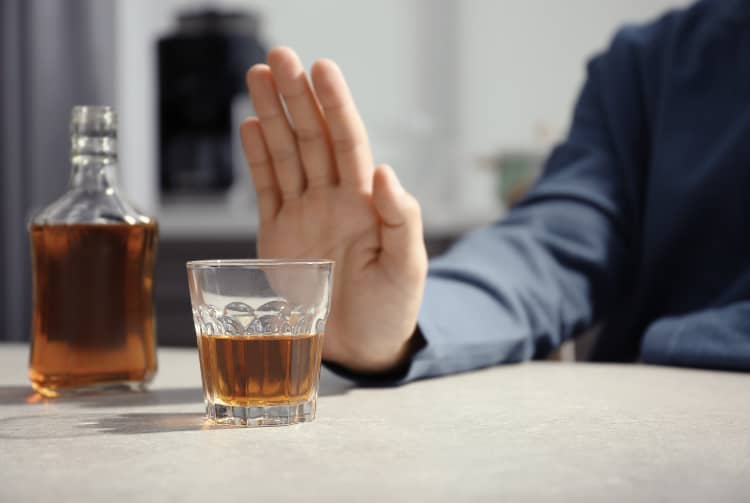 Man pushing away glass of whiskey