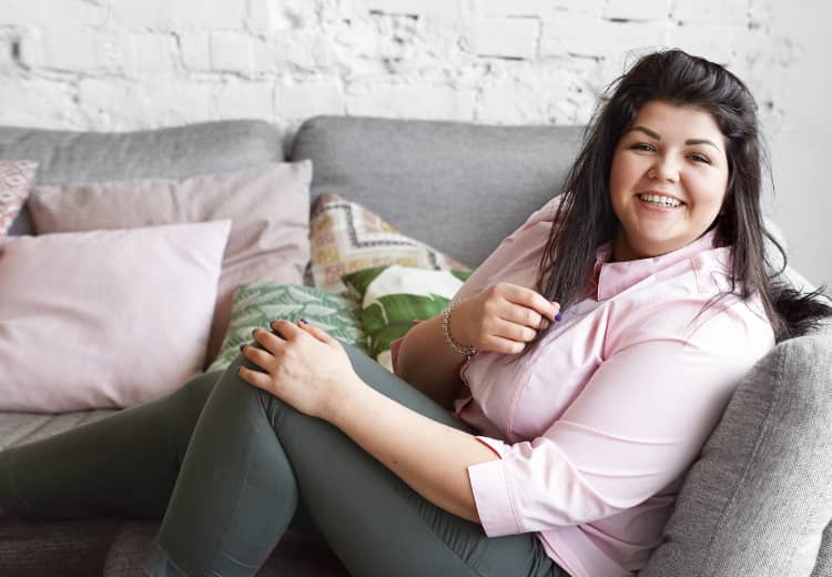 Upbeat overweight woman relaxing on a couch