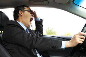 Exhausted driver yawning while at the wheel of a car