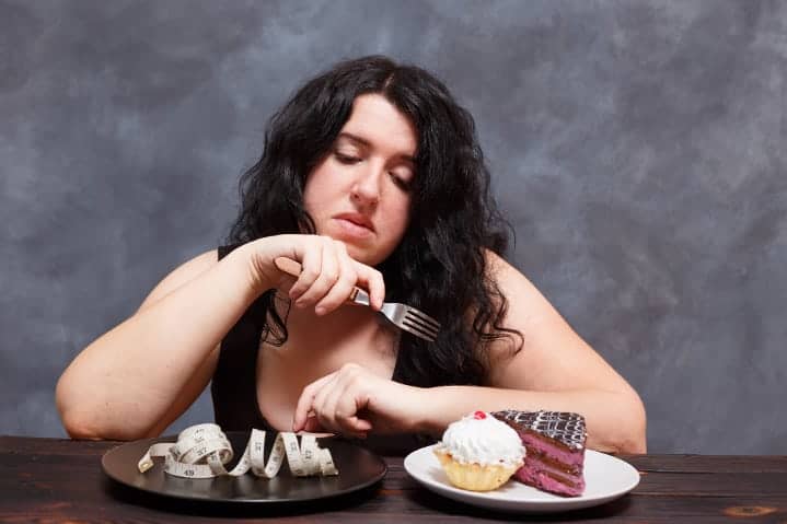 Overweight woman struggling with choice of snack foods over weight loss