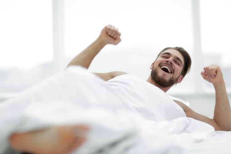 bearded man waking up with a smile on his face after good night's sleep