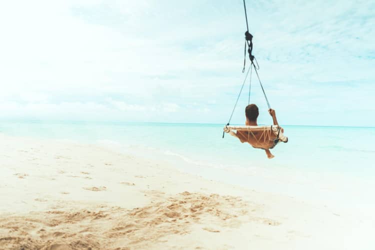 Man relaxing in hanging chair by tropical seashore