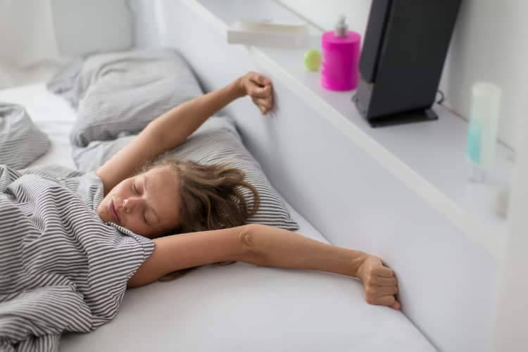 Young woman stretching out in bed after a good night's sleep