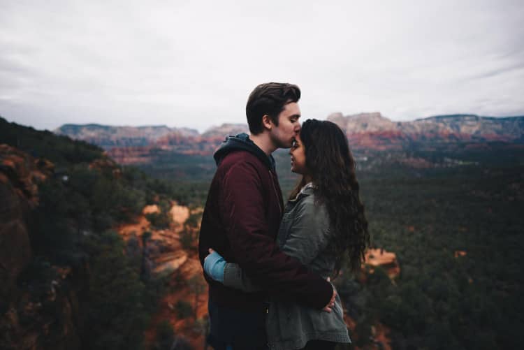 Young couple in jackets kissing on top of western mesa