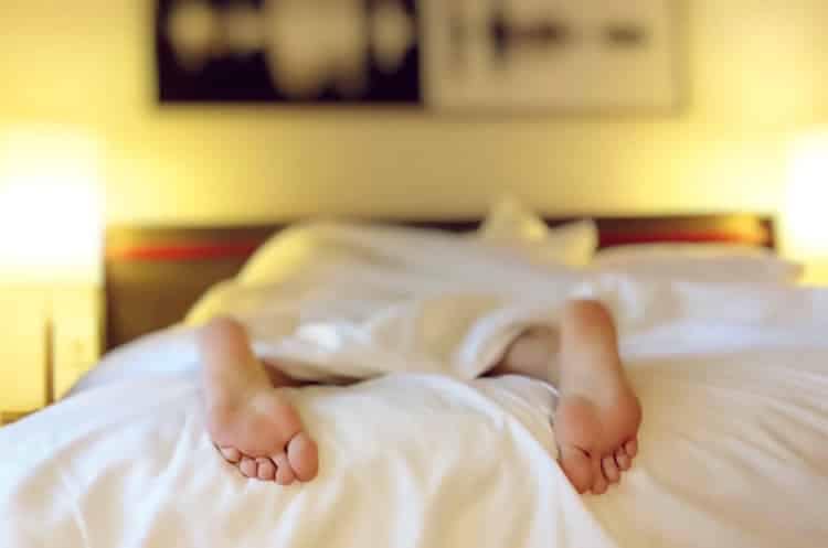 Person sleeping soundly with feet sticking out of bed